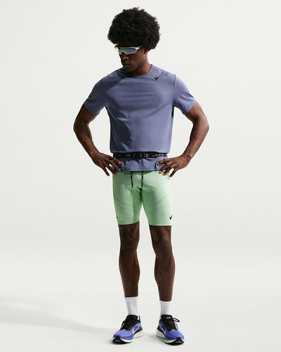 A runner in sunglasses, a lilac T-shirt and light green Nike AeroSwift half tights, standing with hands on hips.