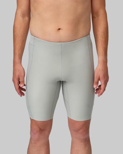A man wearing pale grey-green knee-length running half tights against a grey studio background.